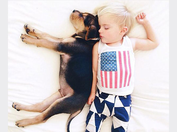 بالصور.. علاقة صداقة قوية تجمع طفل وكلبه تظهر أثناء نومهما